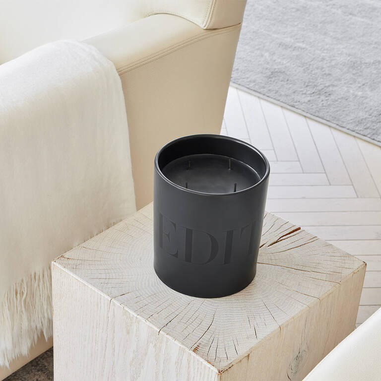 EDITION candle on wood end table next to armchair
