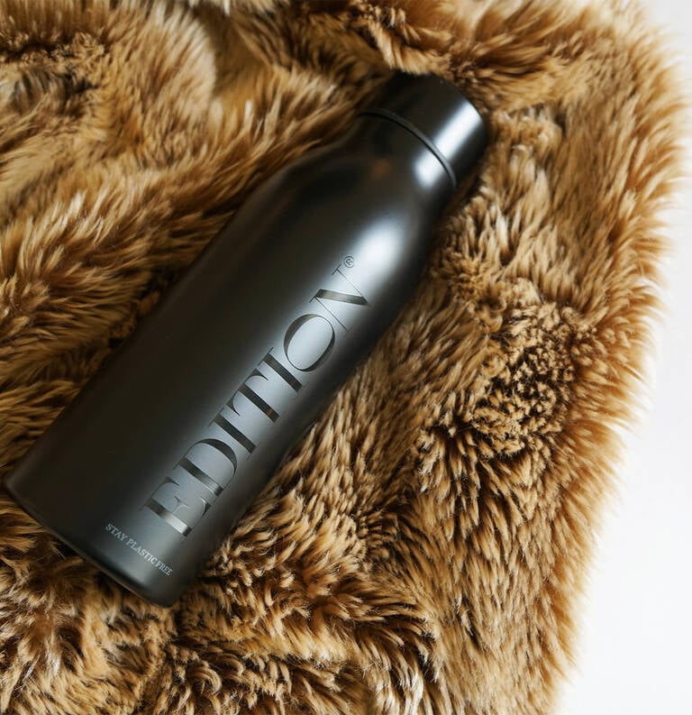 EDITION water bottle laying on top of EDITION signature throw blanket EDITION water bottle laying on top of EDITION signature throw blanket