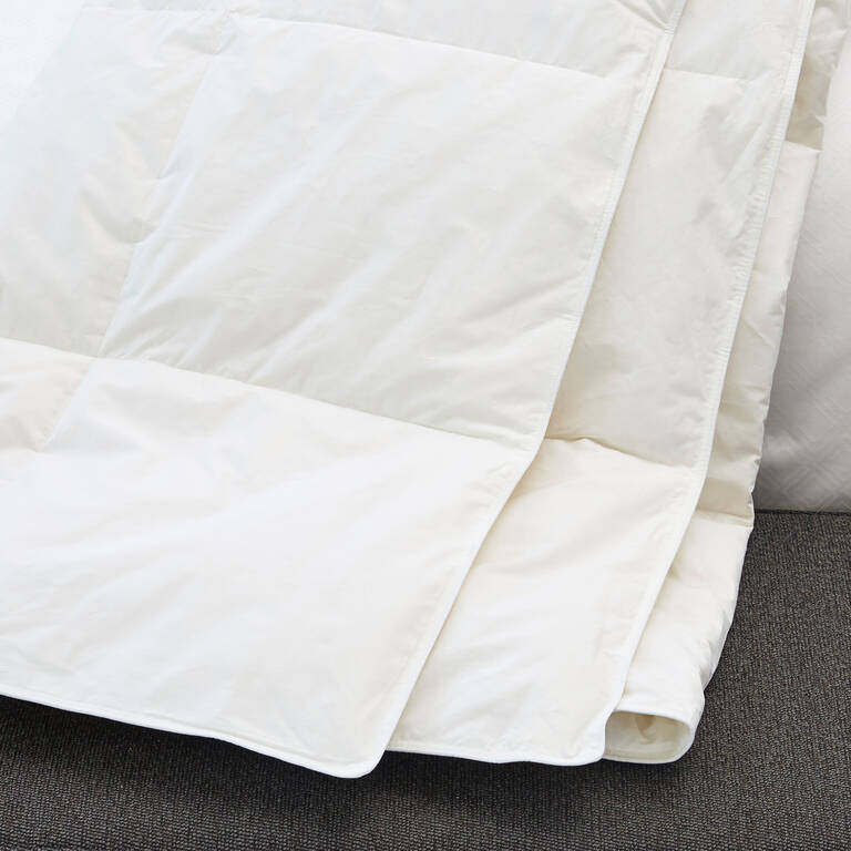 St. Regis lightweight duvet draped over edge of bed