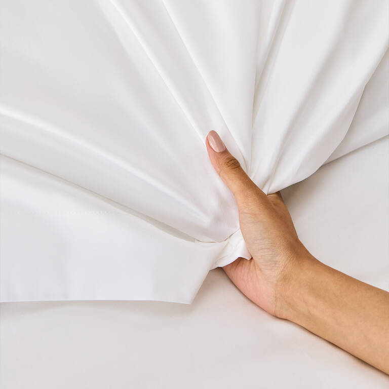 Woman's hand pulling on Marriott Bonvoy Boutiques white sheets