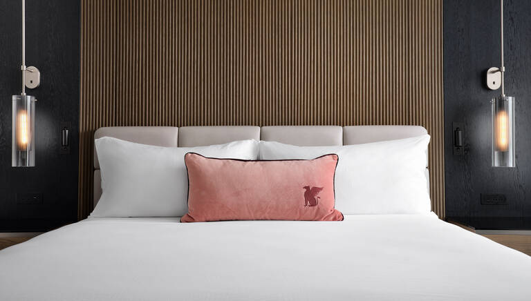 JW Marriott bed in hotel room with logo on an accent pillow