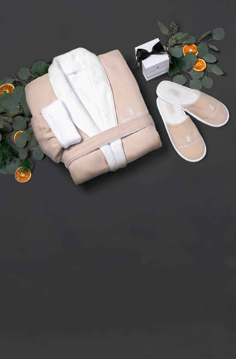 The Ritz-Carlton robe, slippers, and candles with scattered eucalyptus leaves and dried oranges on black background