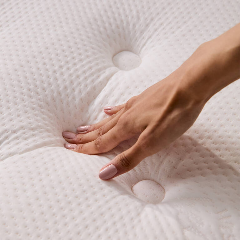Woman's hand pressing down on Marriott Bonvoy mattress to test firmness